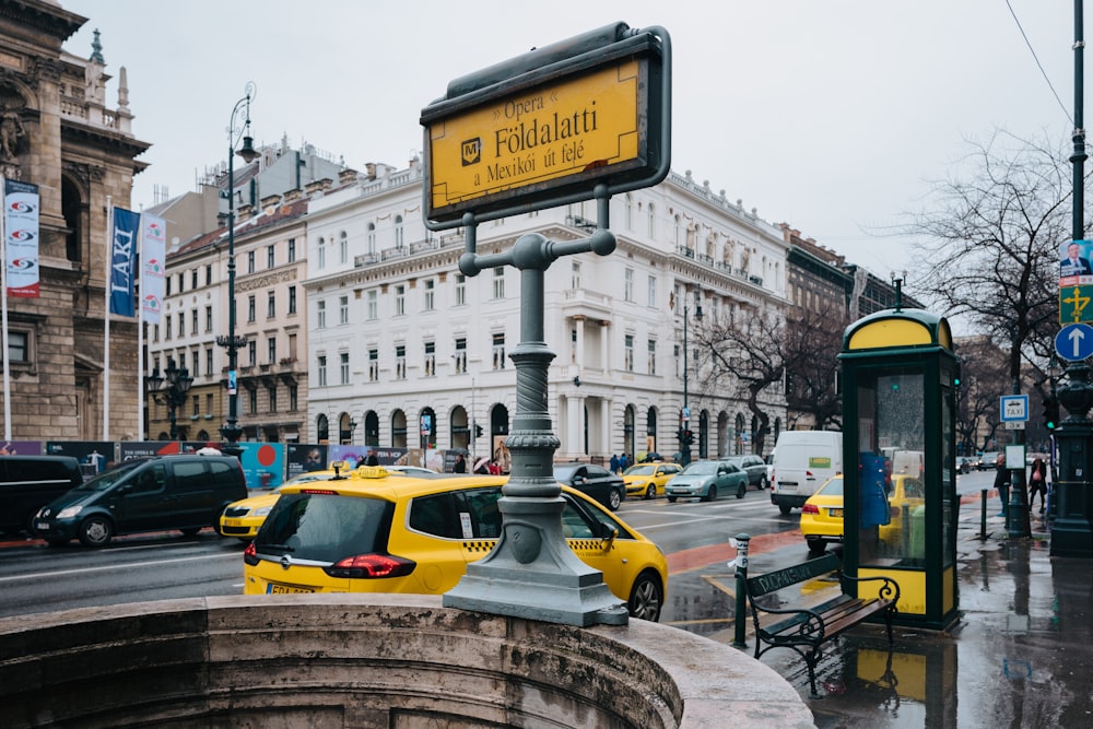 yellow taxi cab on road near white concrete building during daytime