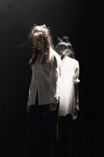 A man and woman standing back to back with a glowing brain between them, dark psychological style with dramatic cinematic lighting and a premium dark green background.