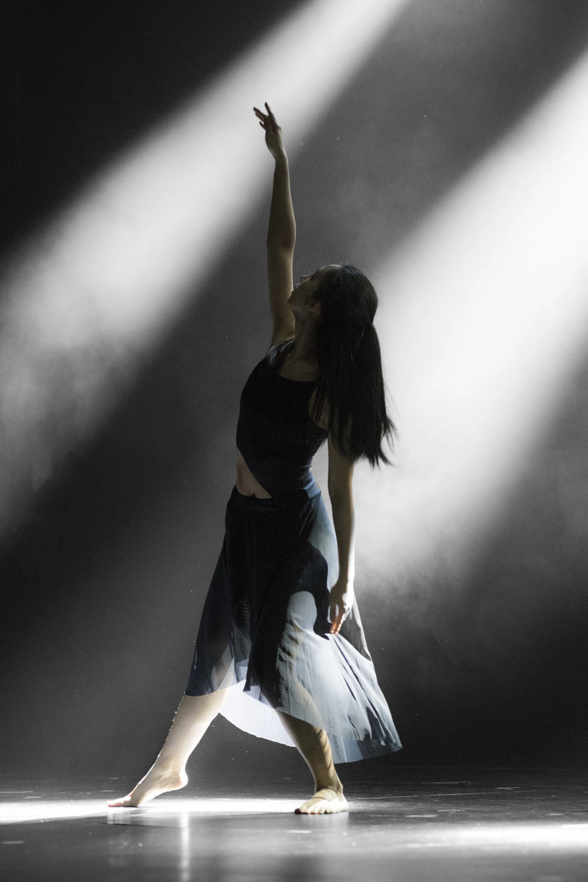 Woman in wide trousers striking a dance pose in black and white