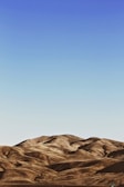 Rolling hills with a smooth, undulating terrain stretch across the landscape under a clear, blue sky.