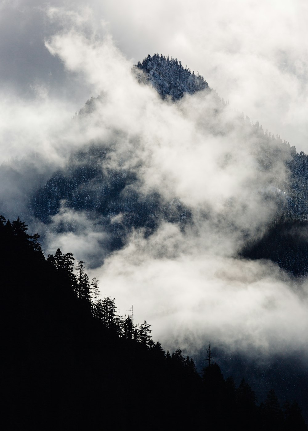 Silhouettenfotografie eines mit Nebel bedeckten Berges