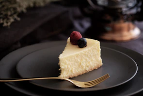 Close-up of a creamy cheesecake topped with vibrant berries, showcasing a rustic wooden background.