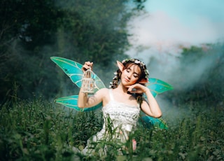 woman in white dress wearing green fairy wings