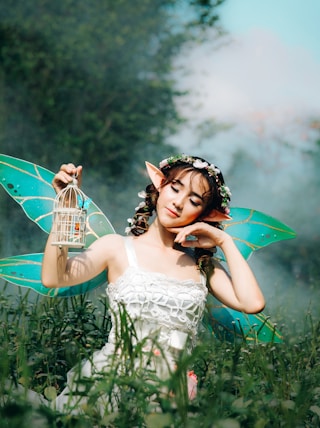 woman in white dress wearing green fairy wings