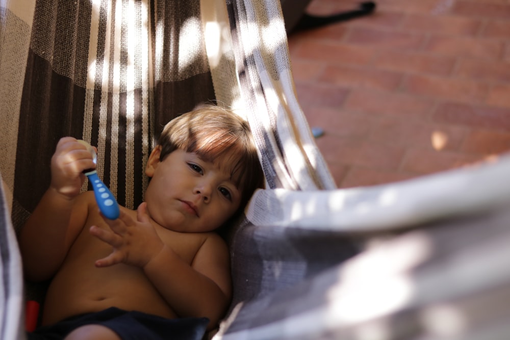 boy holding spoon lying in hammock