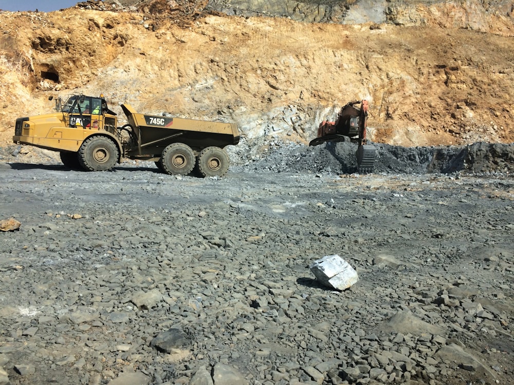 yellow heavy equipment filled with stone by back-hoe