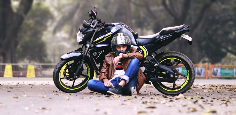 man lying beside black motorcycle