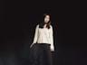 woman standing behind black background