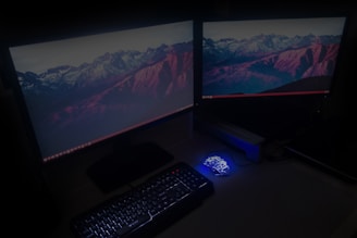 A desktop computer setup with keyboard, mouse, and dual monitors glowing softly.