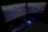 A sleek ultrawide monitor setup with glowing neon blue accents in a dark room.