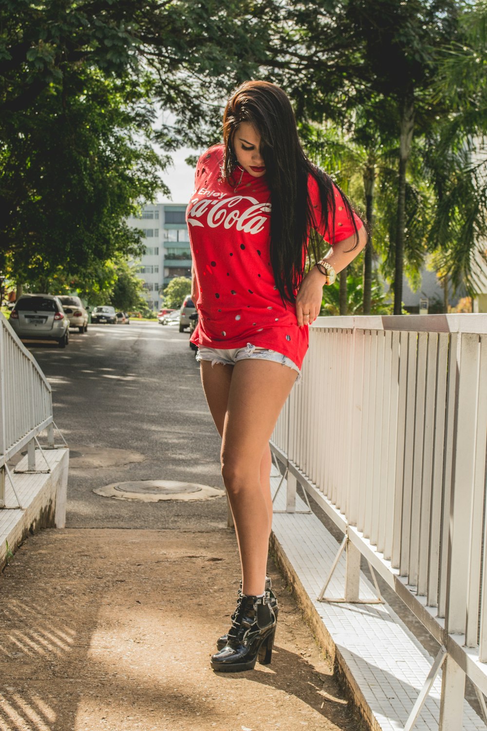 woman standing near white wooden fence looking at her shoes