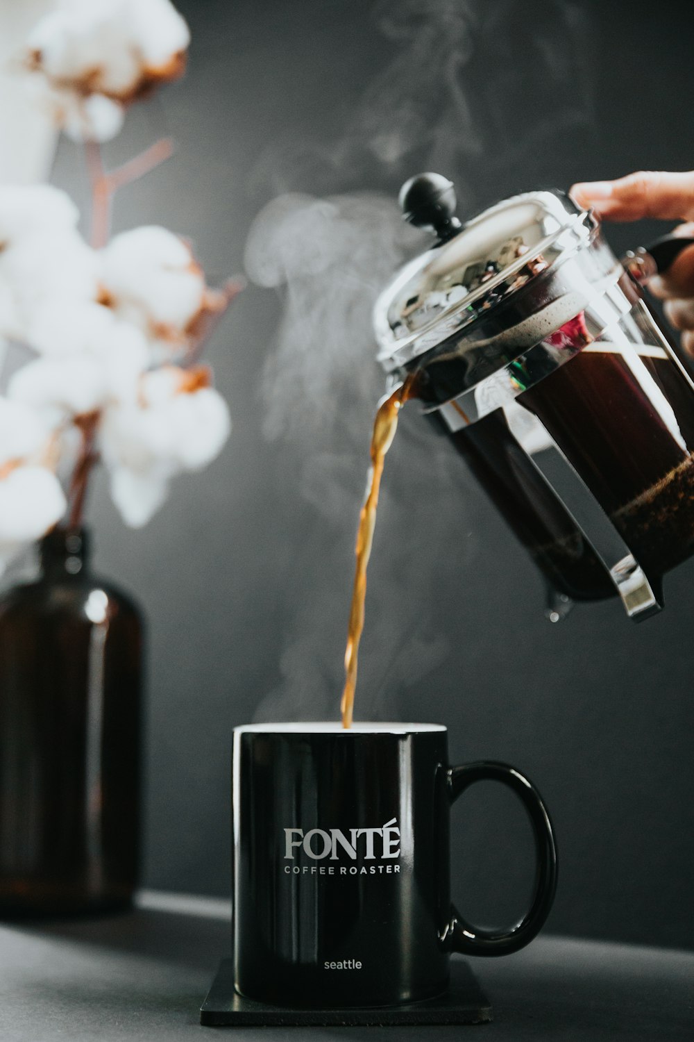 person pouring tea on black ceramic mug