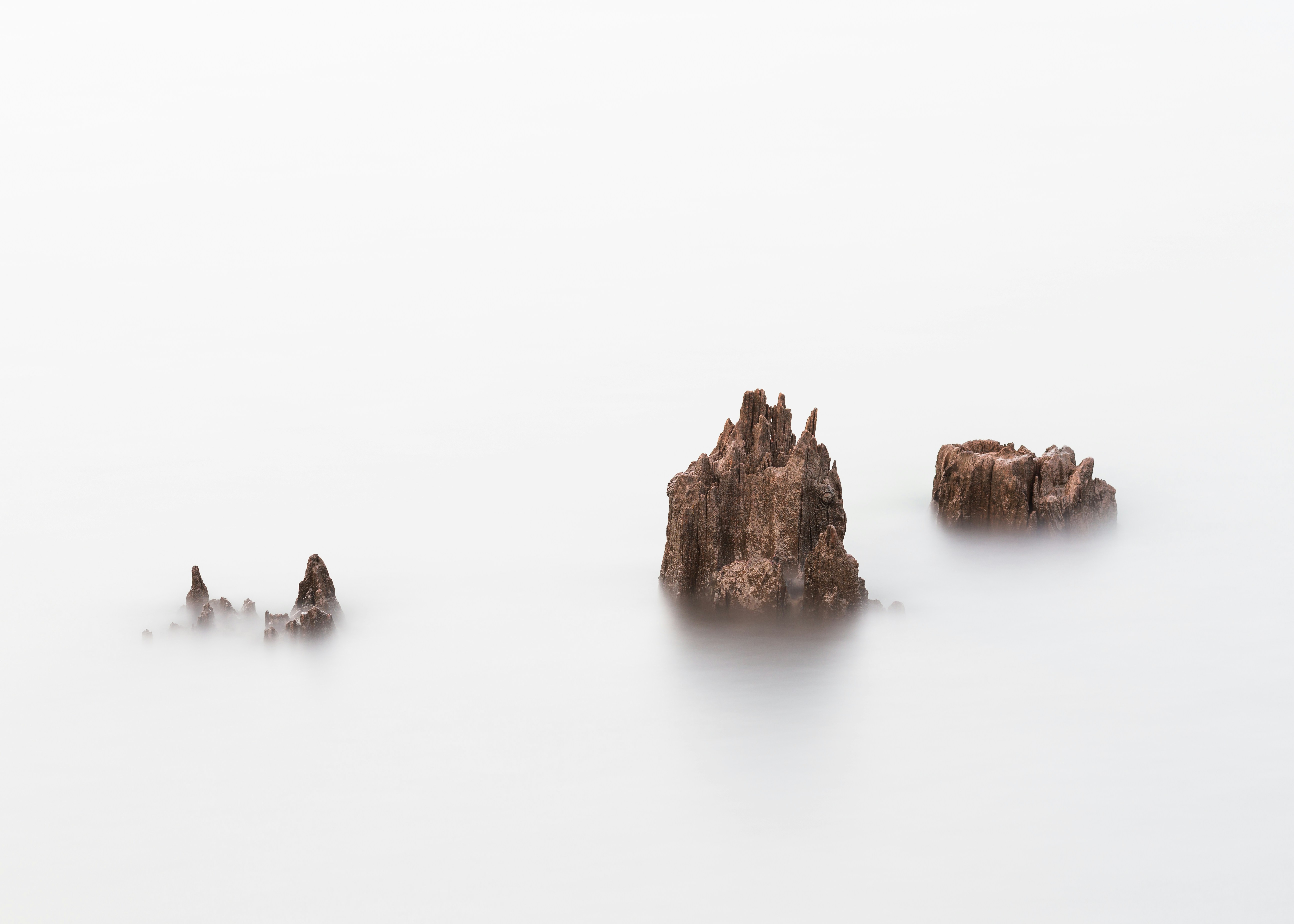 rock formation on body of water, A long exposure of some tree stumps peaking up from the water in Rattlesnake Lake in Washington.