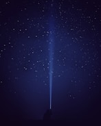 silhouette of person with flash light under starry night