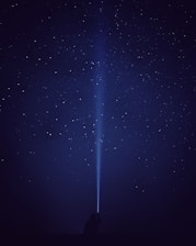 silhouette of person with flash light under starry night