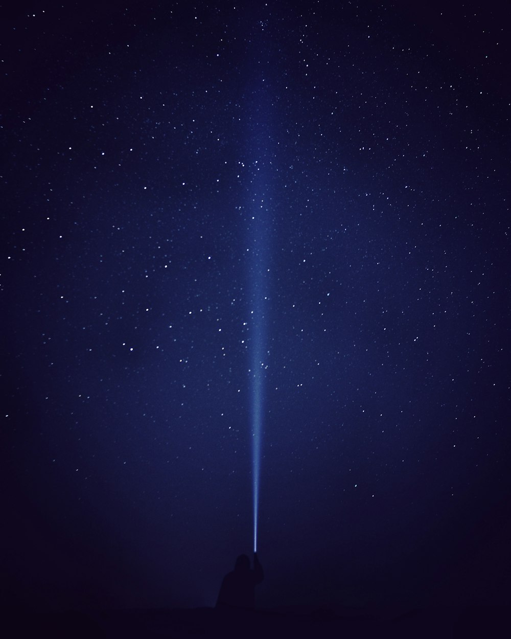 Silhouette einer Person mit Taschenlampe unter Sternennacht