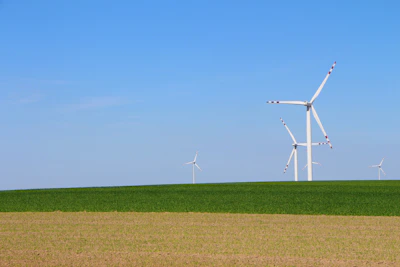 Wind turbine installed on a green farm landscape with blue sky.