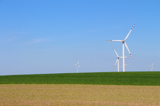 Wind turbines turning gently on a green landscape with a bright blue sky