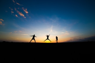 silhouette of three person jumping