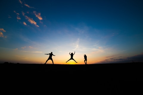 silhouette of three person jumping