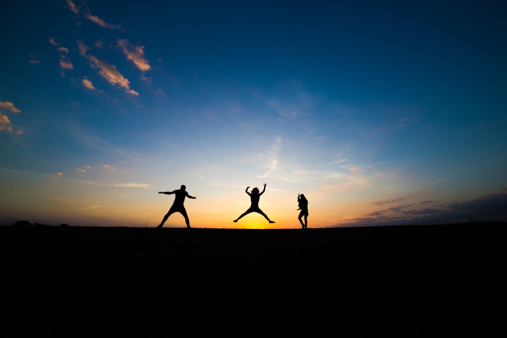 silhouette of three person jumping