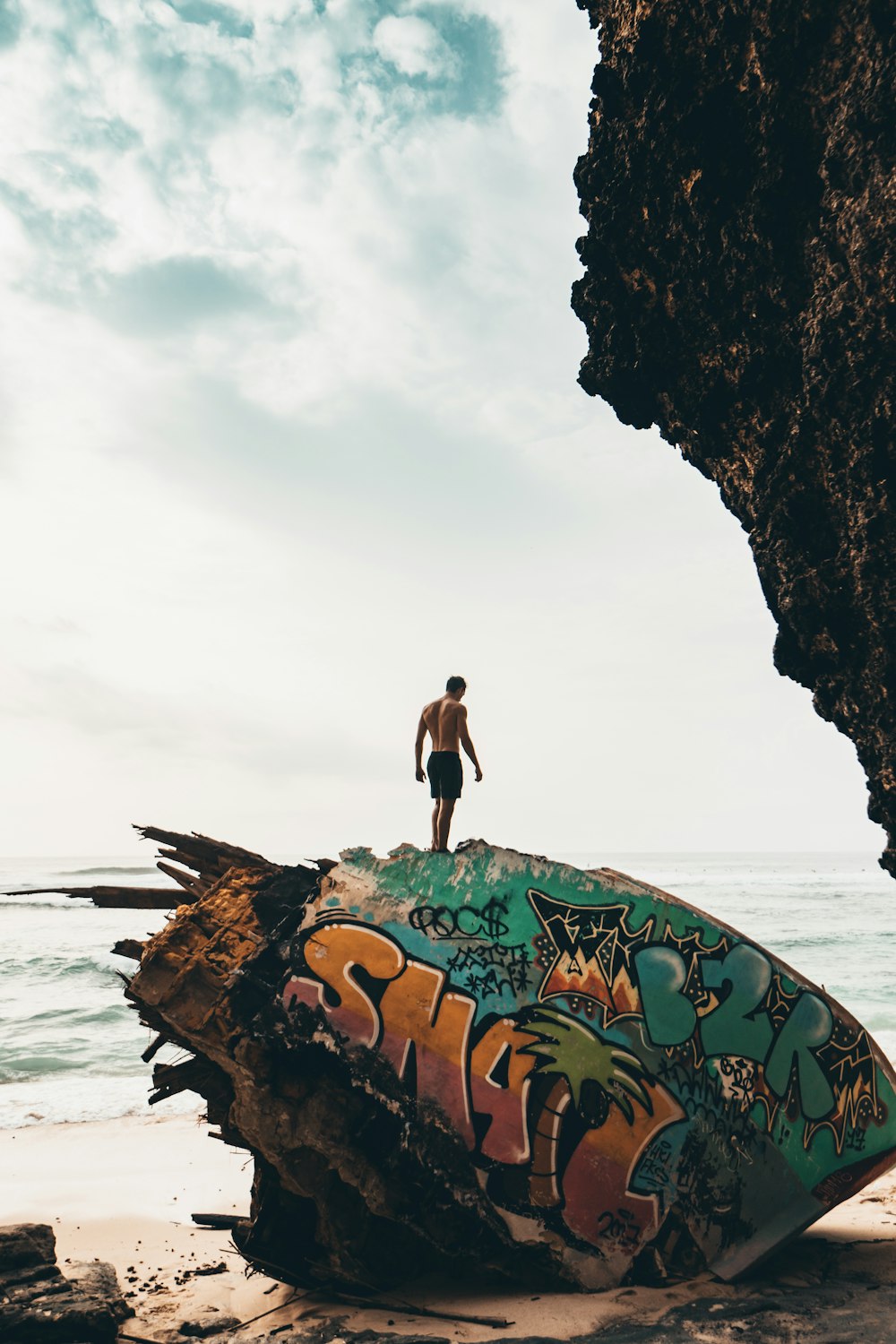 man standing on rock near beachline