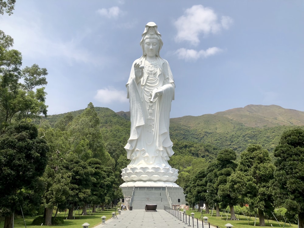 Statue de femme en béton à côté des montagnes