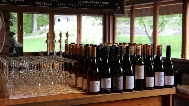 The elegant bar counter at Ampelos lined with a colorful selection of Greek wines ready to be served.