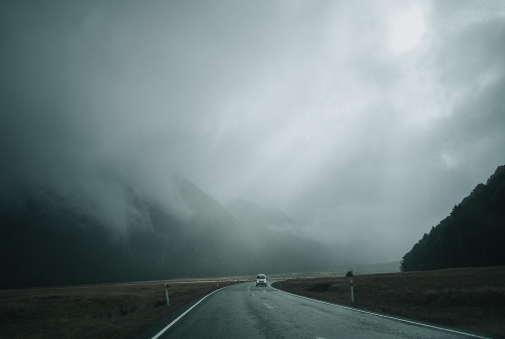 灰色の曇り空の下、アスファルト道路を走る車両