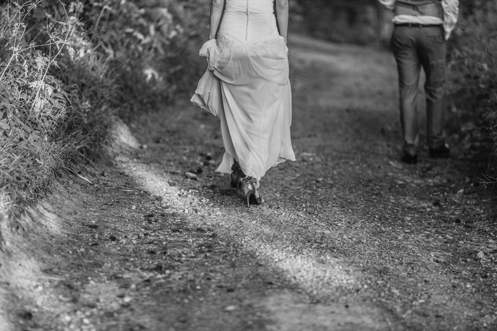 grayscale photography of man and woman walking on pathway
