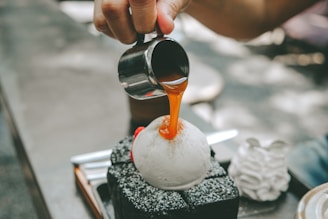 Close-up of a hand carefully placing a caramel topping on a homemade pudding jar in a cozy kitchen setting