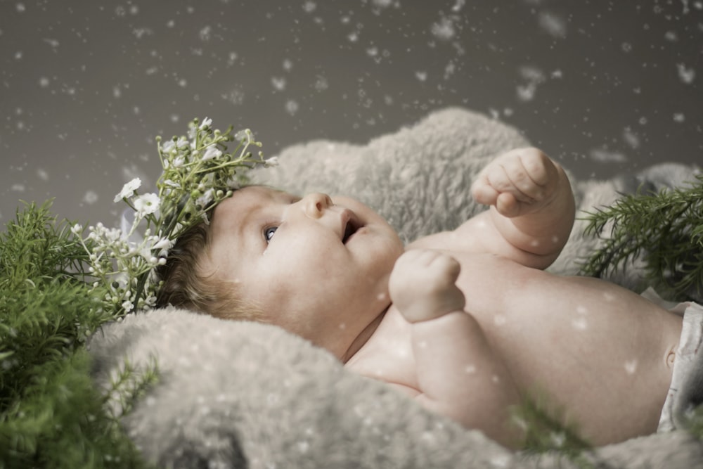 baby lying on gray textile