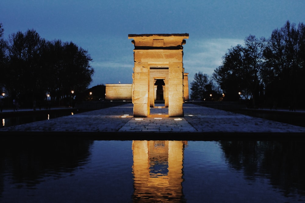 gray arch with lights in middle of water on park