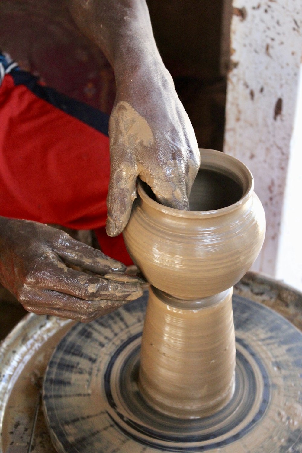 person molding clay pot