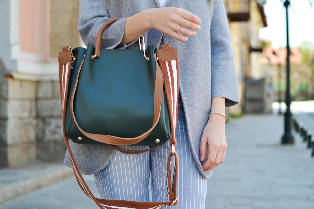 women standing while carrying green and brown leather 2-way shoulder bag