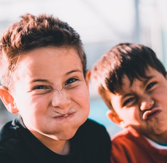 shallow focus photography of two boys doing wacky faces