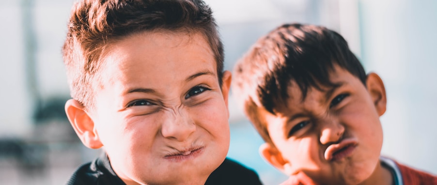 shallow focus photography of two boys doing wacky faces
