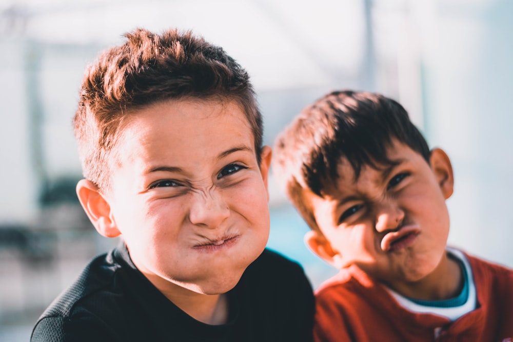 Flachfokusfotografie von zwei Jungen, die verrückte Gesichter machen