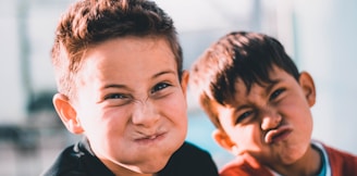 shallow focus photography of two boys doing wacky faces