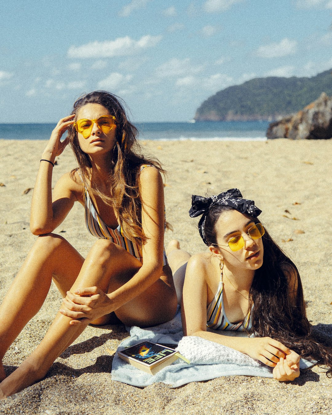 two woman sitting on brown sand