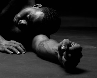 a man laying on the ground with his hands on his knees