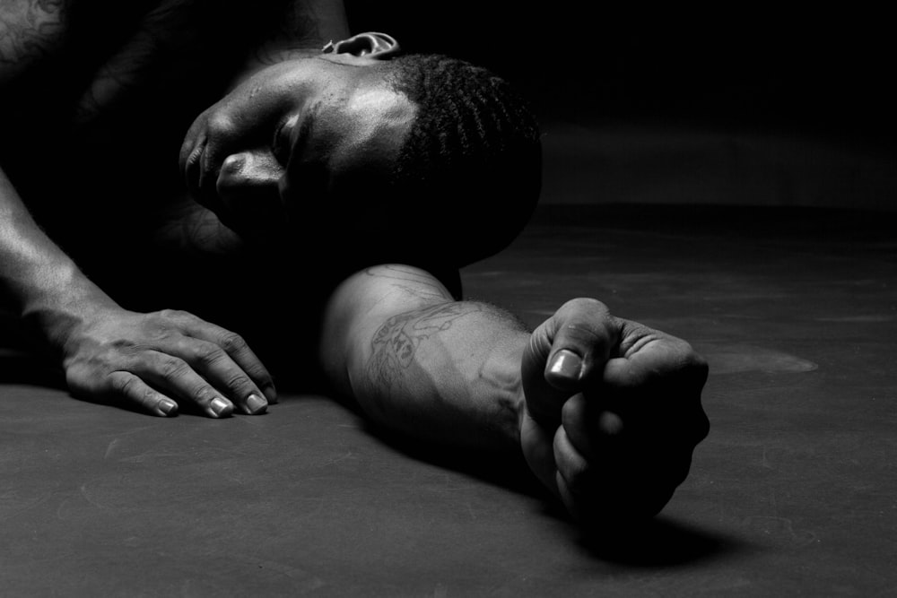 a man laying on the ground with his hands on his knees