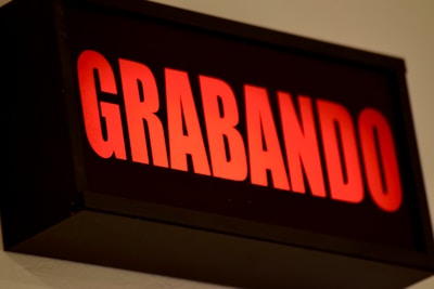 A red illuminated sign displaying the word 'GRABANDO' in bold uppercase letters against a dark background. The lighting suggests it is a signal for recording in progress.