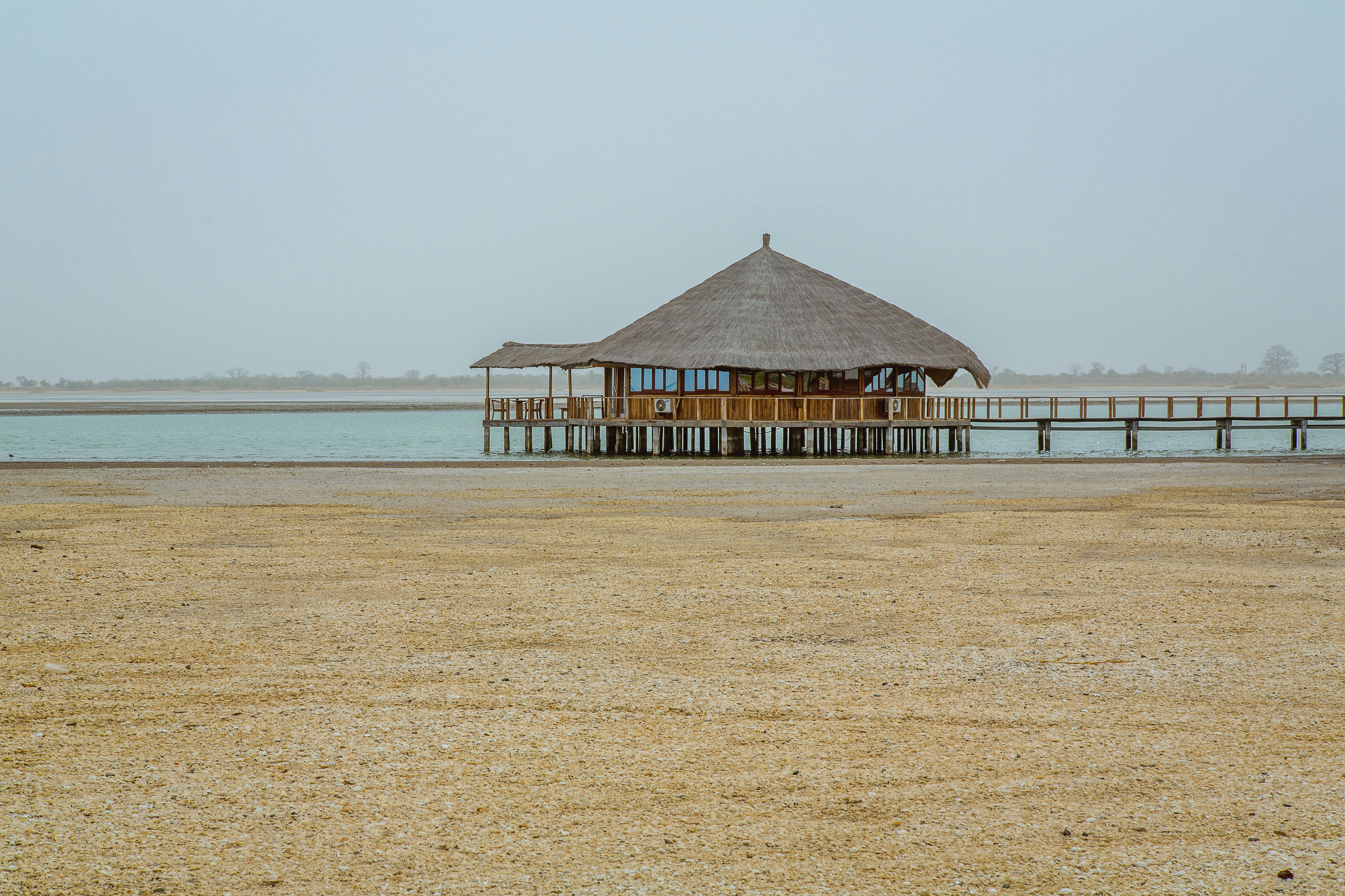 brown wooden hut above water near shore at daytime
