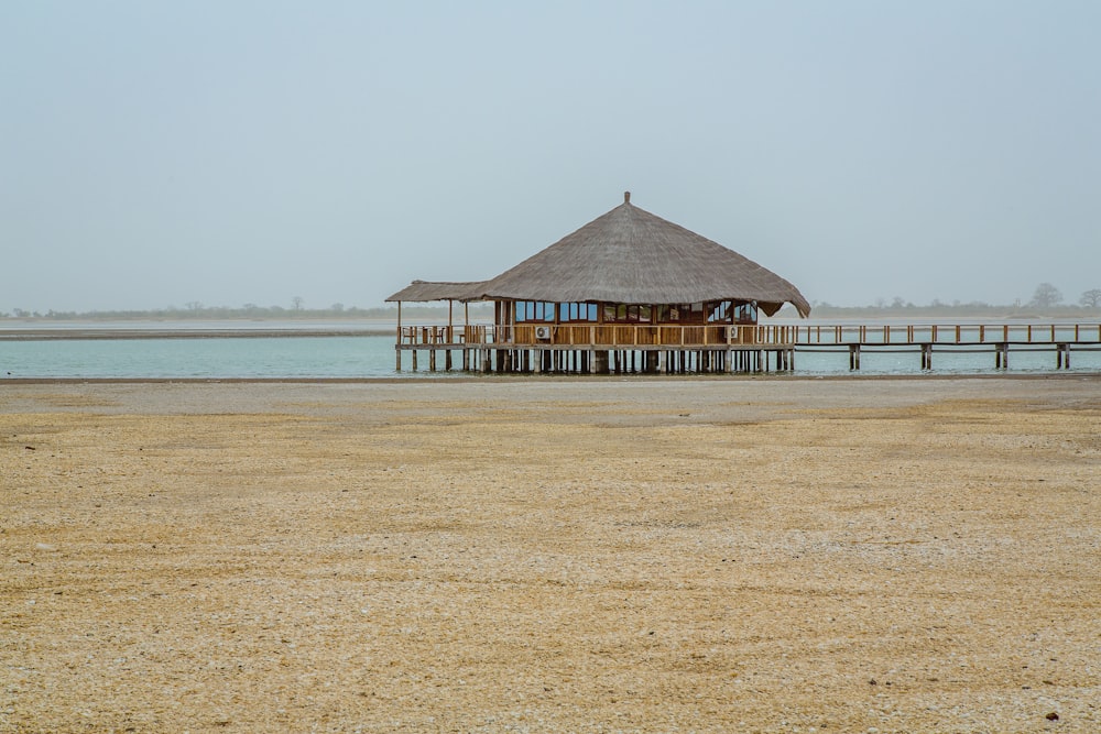 brown wooden hut above water near shore at daytime