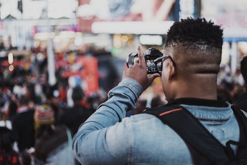 selective focus photography of man capturing people using DSLR camera during daytime