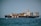 A large cargo ship is sailing on the ocean, loaded with numerous colorful shipping containers stacked on its deck. The ship has a black hull and white superstructure, with the letters 'MSC' prominently displayed on the side. The background is a clear horizon with a slightly overcast sky.
