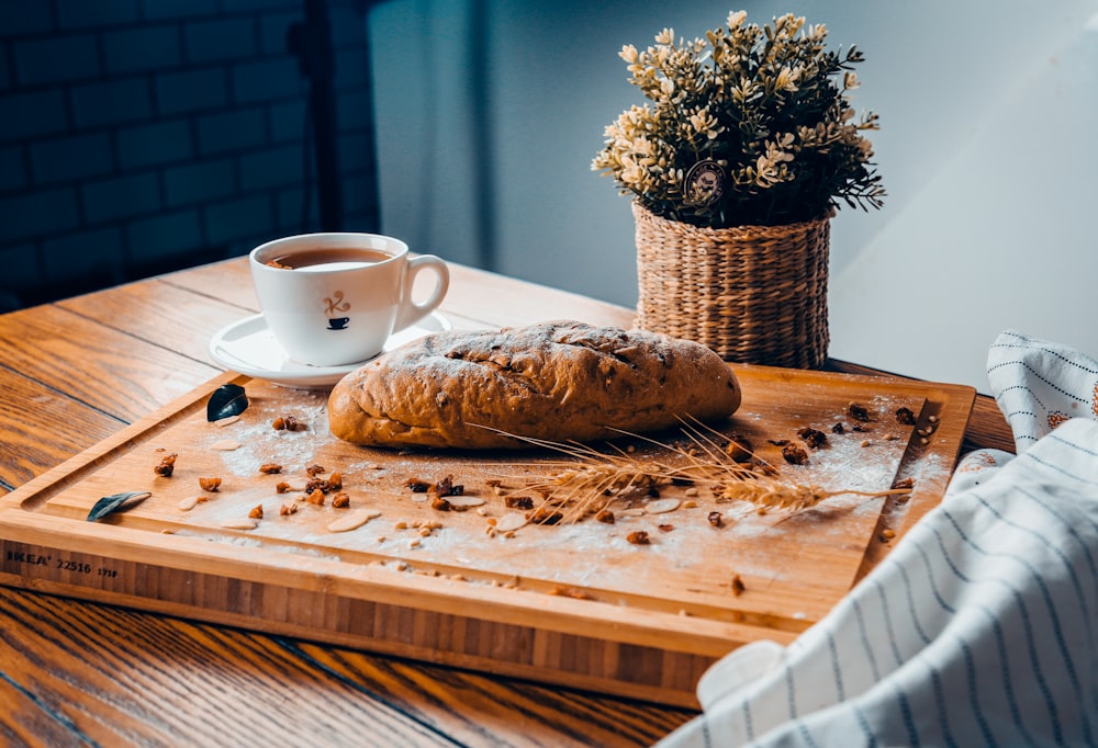 baked bread near cup of coffee both on brown wooden board