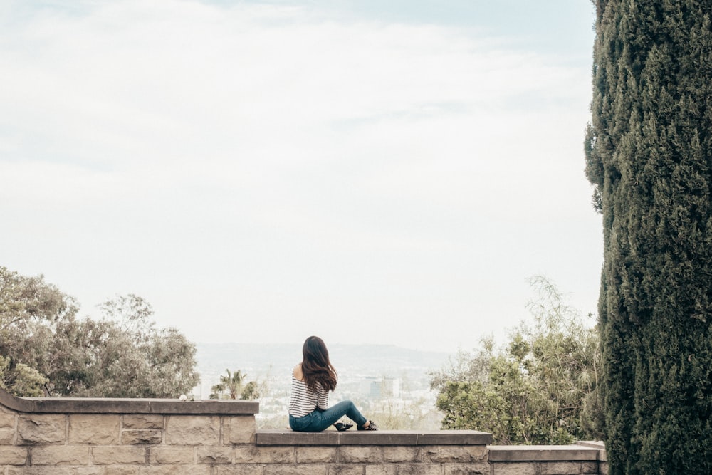 woman sitting on concrete fence