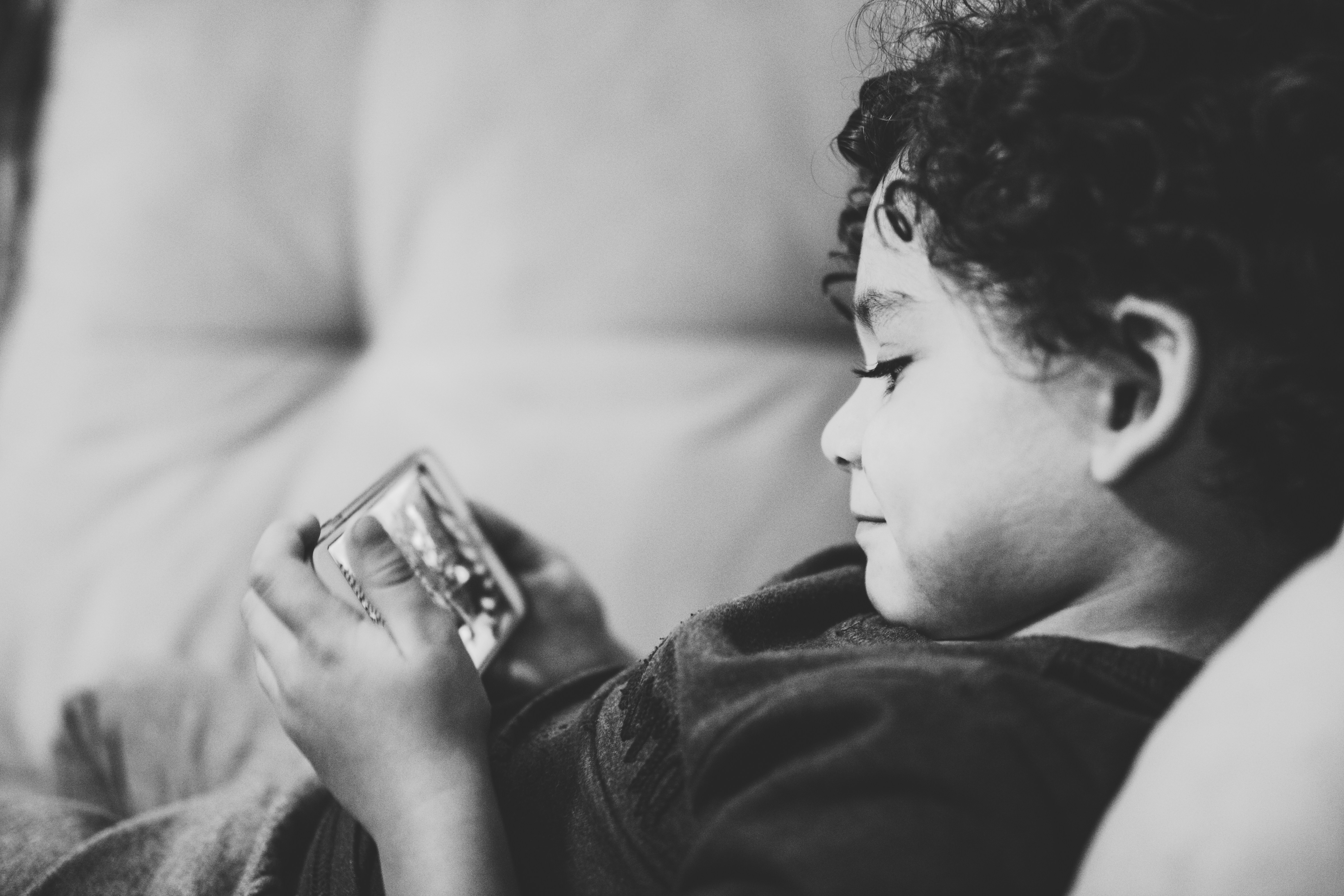grayscale photography of child lying on bed